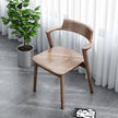 Wooden chair in a room with a potted plant and white curtains.