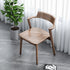 Wooden chair in a room with a potted plant and white curtains.