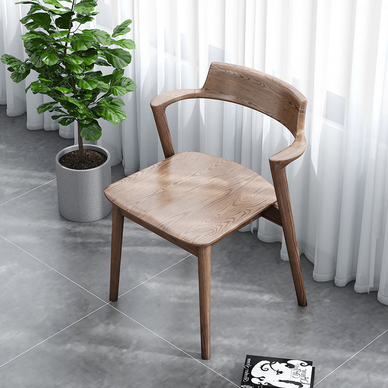 Wooden chair in a room with a potted plant and white curtains.