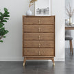 Wooden dresser with gold knobs in a room setting with plants and decor.