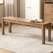 Wooden table with an open book on a textured rug in a room setting.