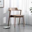 Wooden chair in a room with white curtains and a gray floor.
