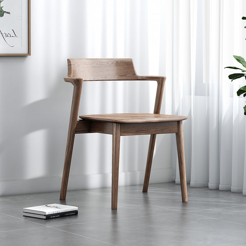 Wooden chair in a room with white curtains and a gray floor.