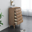 Wooden dresser with multiple drawers in a room with a plant and framed picture.