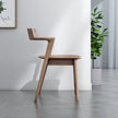 Wooden chair in a room with a plant and framed picture on the wall.