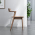 Wooden chair in a room with a plant and framed picture on the wall.