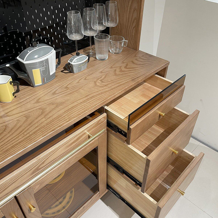 Wooden sideboard with open drawers and kitchen items on a countertop.