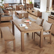 Wooden dining table set with chairs and a bench in a living room.