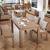 Wooden dining table set with chairs and a bench in a living room.