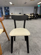 A black wooden chair with a white seat in a showroom, featuring clean lines and a versatile design.