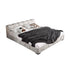 Gray upholstered bed with white bedding and a gray blanket on a white background