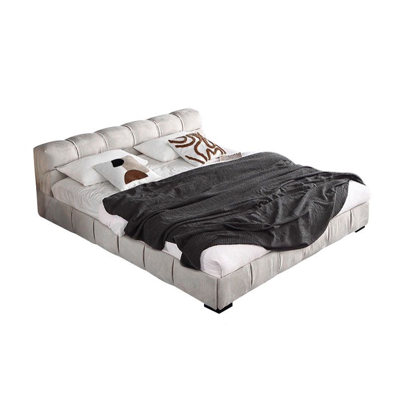 Gray upholstered bed with white bedding and a gray blanket on a white background